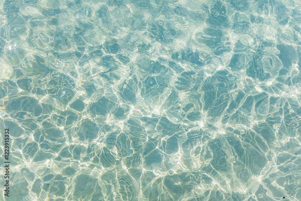Obraz premium Rippled surface of clear turquoise water with sunlight reflections creating a sparkling natural pattern. 