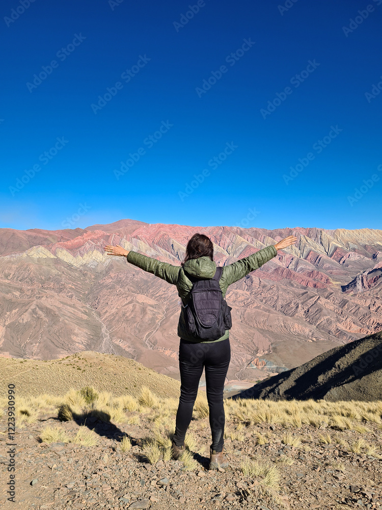 Fototapeta premium Woman with backpack looking at colorful mountains