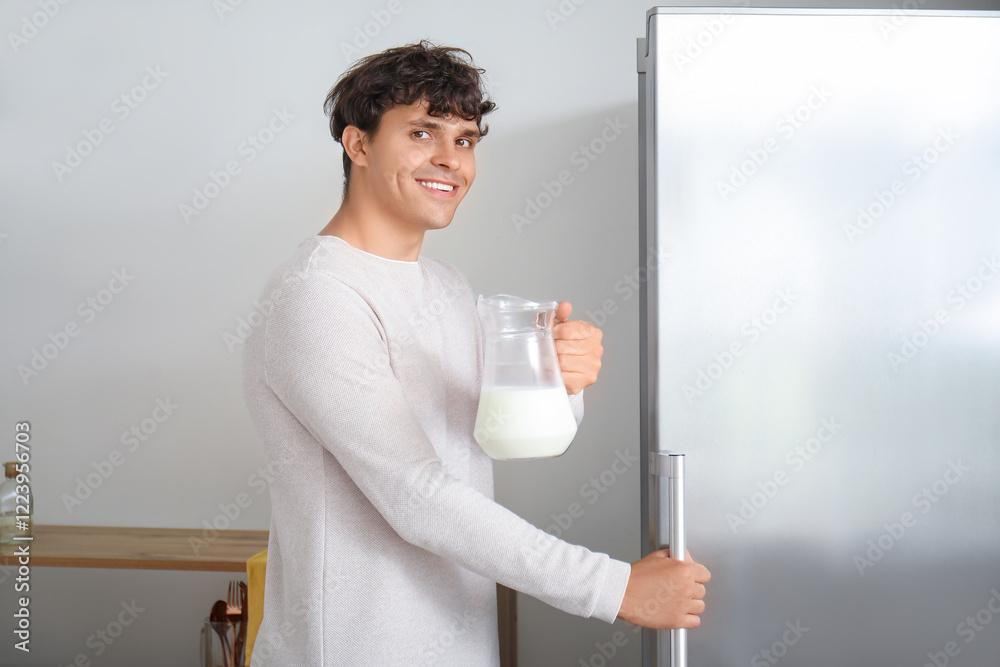Young man taking jug of milk from fridge in kitchen Young man taking jug of milk from fridge in kitchen