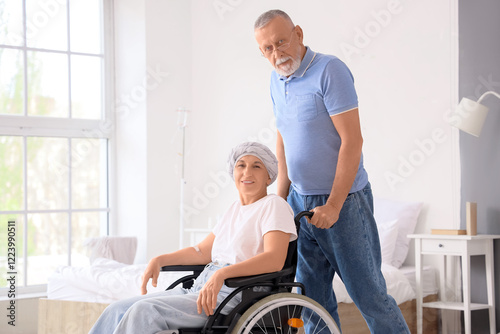 Mature woman after chemotherapy in wheelchair with her husband at home