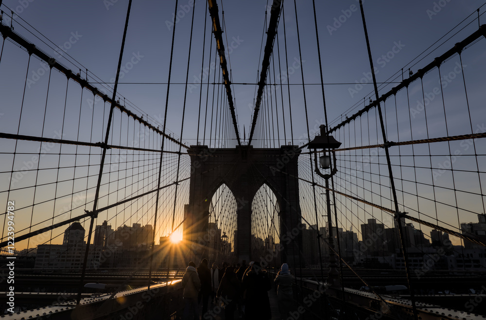 Obraz premium brooklyn bridge at sunrise (new york city landmark over east river to manhattan) travel tourism famous destination in usa america united states (suspension cables lamp light streetlight) people cross