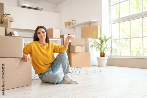 Beautiful woman with key from new flat and boxes sitting in kitchen on moving day