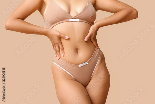 Beautiful young African-American body positive woman on beige background, closeup