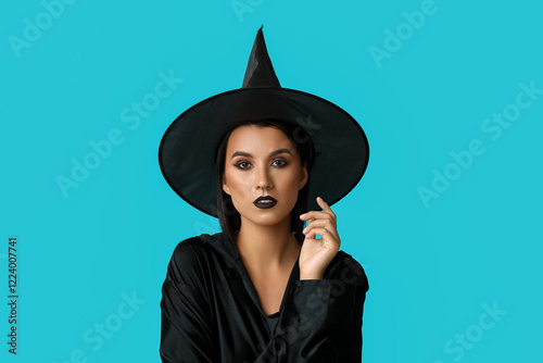 Beautiful young witch on blue background photo