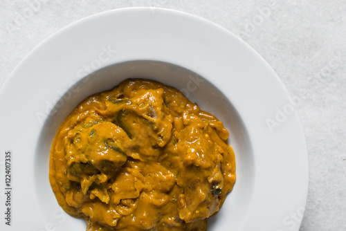 Overhead view of Nigerian owo soup with fish and beef in a white plate, top view of oghwo soup in a large dinner plate, traditional owo soup in a white dish photo