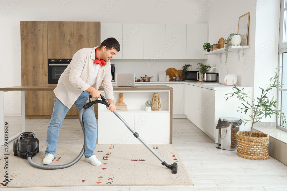 Fototapeta premium Young man vacuuming living room carpet, modern home cleaning routine, domestic chores and household maintenance
