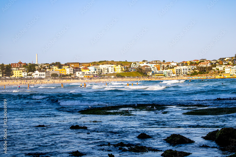 A stunning beach scene at Bondi Beach, Sydney, featuring green moss-covered rocks and vibrant splashing waves, with the picturesque buildings in the background creating a perfect coastal view. A stunning beach scene at Bondi Beach, Sydney, featuring green moss-covered rocks and vibrant splashing waves, with the picturesque buildings in the background creating a perfect coastal view.