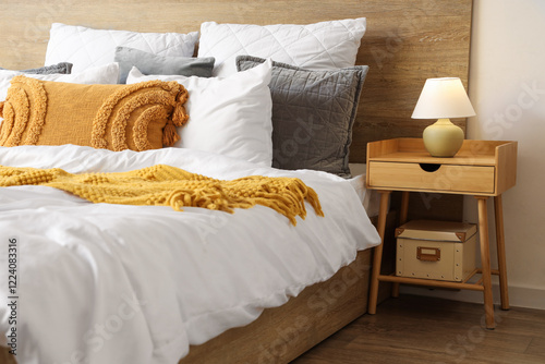 Interior of stylish bedroom with cozy bed and lamp on bedside table