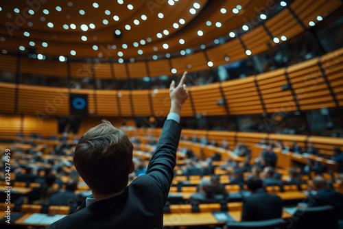 A person in the international meeting room  is raising their hand to a large audience sitting and listening in a conference hall with wood paneling, with a blurred background, photo