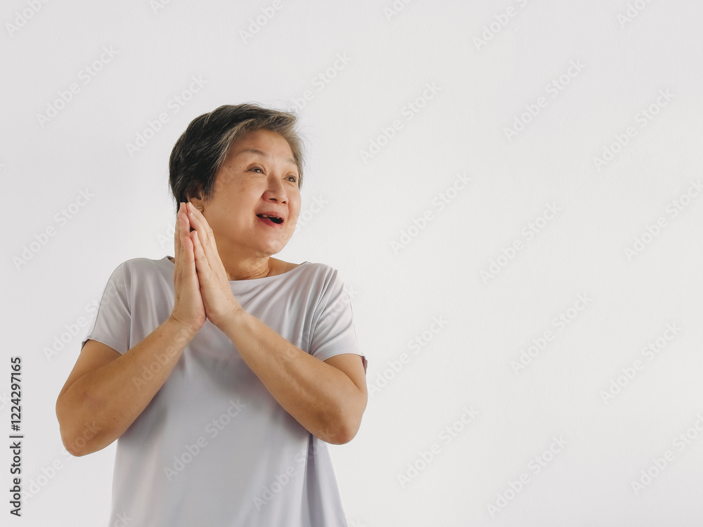 Asian elder woman feeling happy and grateful, two hands palm touching, praying hands gesture, smiling while standing isolated over white background wall. Asian elder woman feeling happy and grateful, two hands palm touching, praying hands gesture, smiling while standing isolated over white background wall.