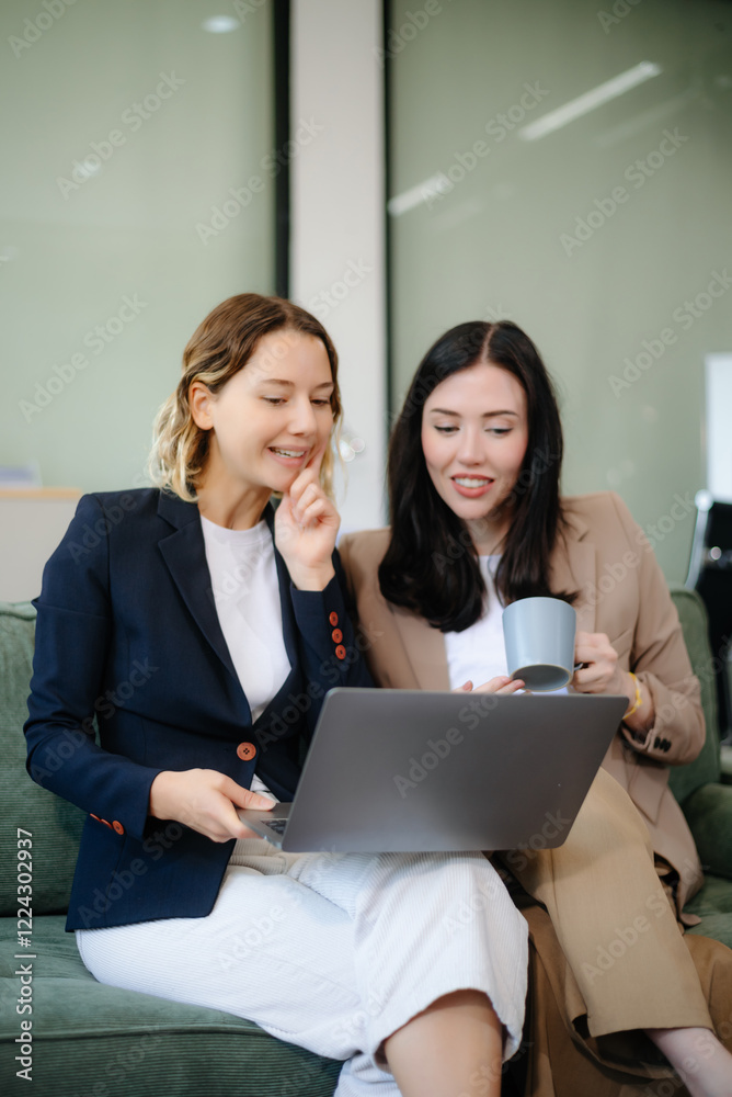 Two women collaborating on a project on sofa at home, brainstorming with a laptop and notebook Two women collaborating on a project on sofa at home, brainstorming with a laptop and notebook
