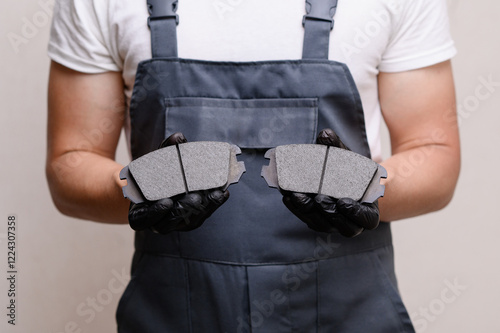 Auto mechanic holds brake pads of car in hands in black gloves, close-up. Concept auto parts replacement, car maintenance, brake system serviceability photo