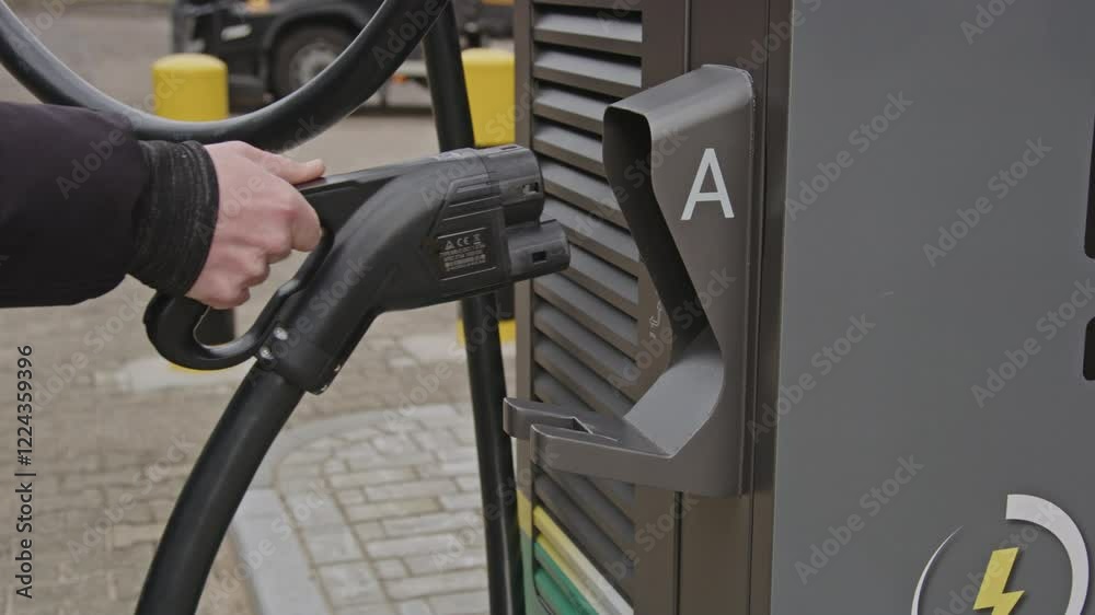 Hand placing the plug of an EV charging station back into the large station in slow motion Hand placing the plug of an EV charging station back into the large station in slow motion