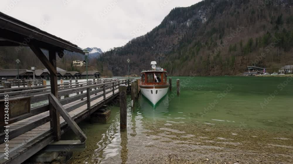 Electric boat in Konigssee Lake, Bavaria, Germany, serene ride on crystal-clear water surrounded by cliffs, establishing static of ferry in water Electric boat in Konigssee Lake, Bavaria, Germany, serene ride on crystal-clear water surrounded by cliffs, establishing static of ferry in water
