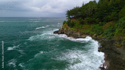 Aerial drone view of coastline with hills and trees, as well as view of coral cliffs and sea with waves from the ocean in Lampon Kebumen Central Java Indonesia photo