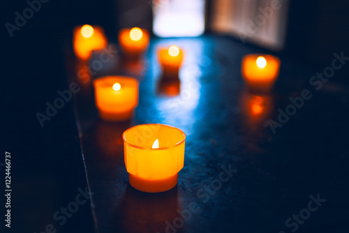 Obraz na płótnie Dark surface with glowing orange candles. The candles emit a warm light, creating a cozy atmosphere. Light from a window can be seen in the background. Praying indoor the church w salonie