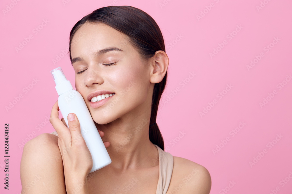 Young woman, holding a skincare product, enjoying a moment of self care on a pink background, highlighting beauty, wellness, and confidence in skincare Young woman, holding a skincare product, enjoying a moment of self care on a pink background, highlighting beauty, wellness, and confidence in skincare