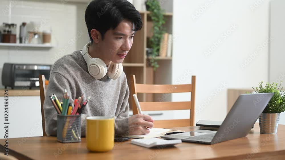 Attractive happy young Asian student studying at the college library, sitting at the desk Attractive happy young Asian student studying at the college library, sitting at the desk