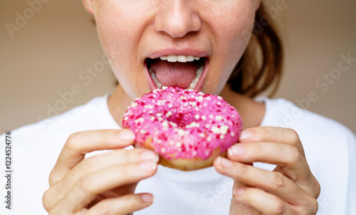 Closeup photo woman eating donut with pink glaze