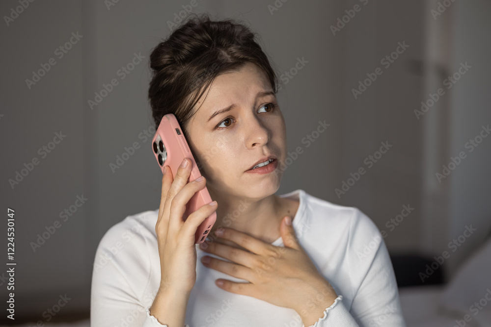 Concerned woman communicates over phone while sitting indoors in a cozy environment Concerned woman communicates over phone while sitting indoors in a cozy environment