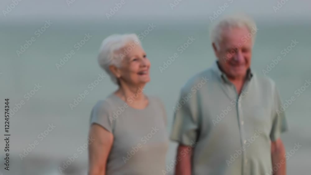 Elderly couple walking on beach at sunset Elderly couple walking on beach at sunset