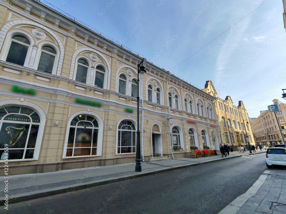 Obraz premium historical pink building with multiple floors, adorned with decorative features and air conditioning units on its windows. The combination of classic design and modern amenities highlights urban