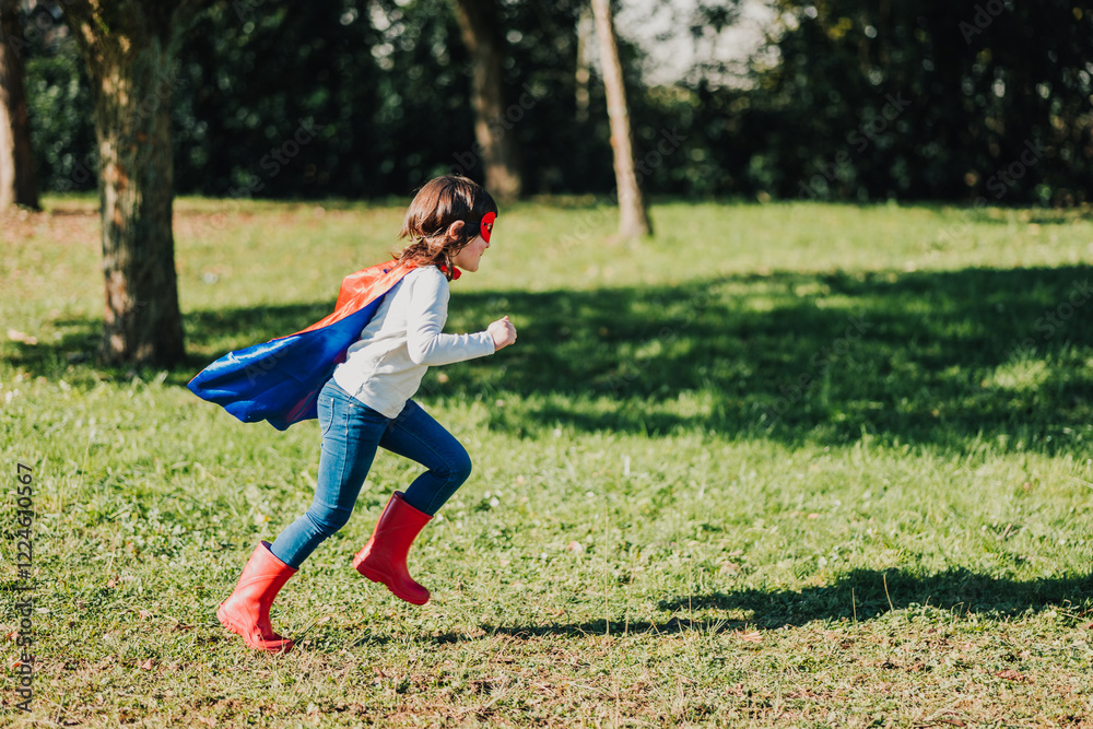 Child in superhero costume runs joyfully across a grassy field on a sunny day Child in superhero costume runs joyfully across a grassy field on a sunny day