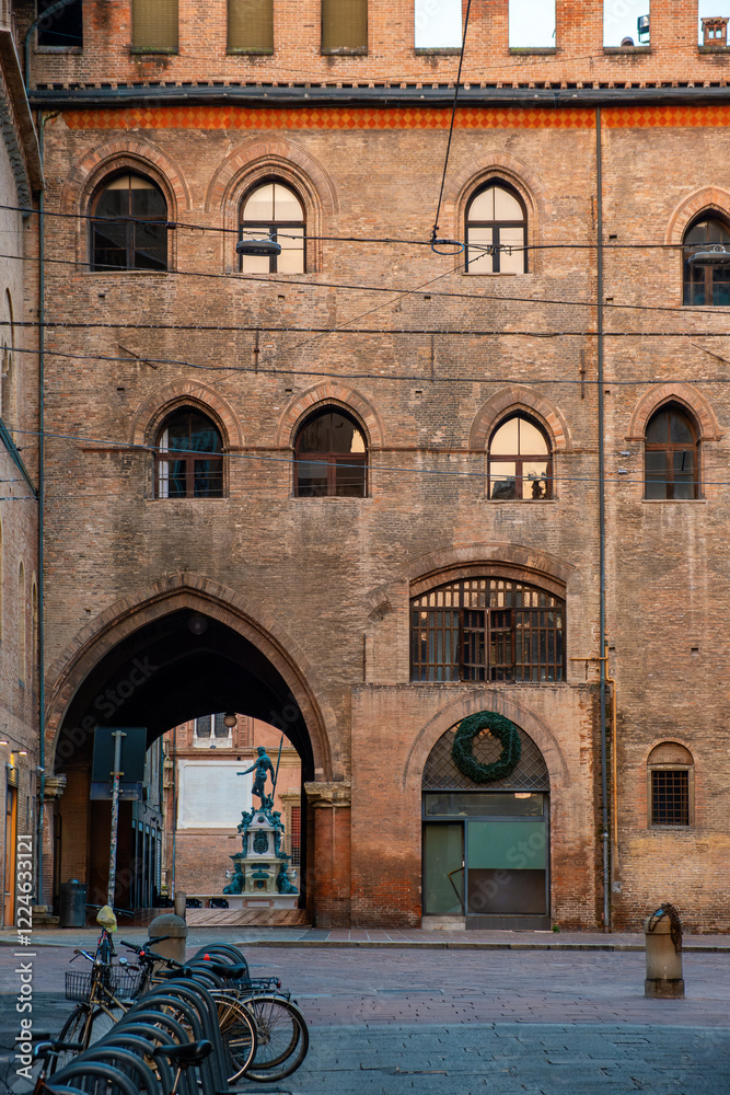 Obraz premium Narrow street in Bologna old town, Emilia Romagna, Italy, featuring historic architecture and the iconic Palazzo del Podesta at sunrise with nobody. Vertical orientation. Travel destination in Europe