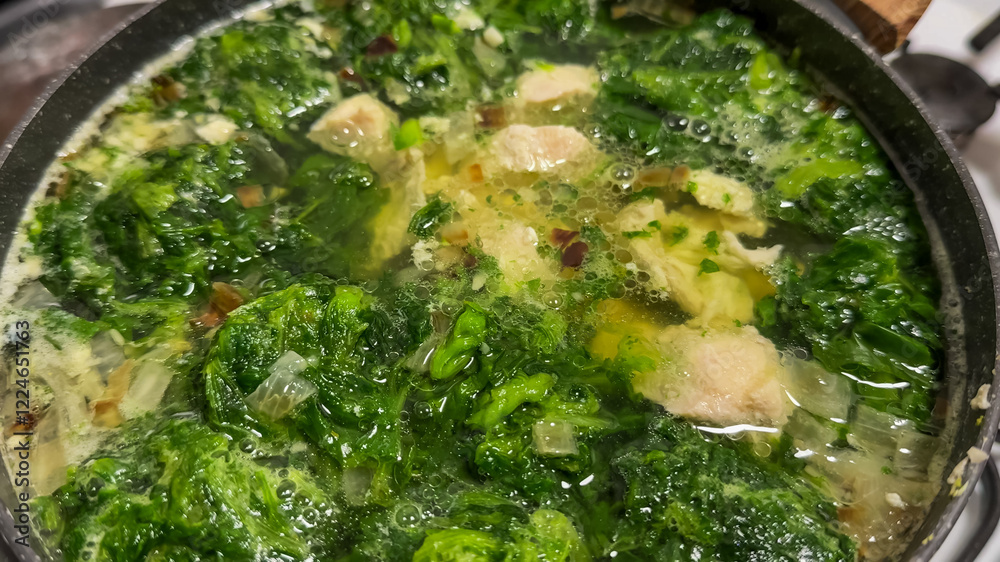 A pot of green soup simmering on the stove, representing healthy eating and homemade comfort during winter holidays A pot of green soup simmering on the stove, representing healthy eating and homemade comfort during winter holidays