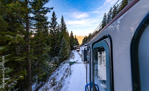 View from a cogwheel train traveling downhill from the Zugspitze in the direction of Garmisch-Partenkirchen (Germany) shortly before meeting the railcar traveling uphill in snowy winter scenery.