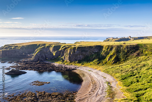 The cliffs and beach at Strathlethan Bay, near Stonehaven in Aberdeenshire, with Dunnottar Castle in the distance. Taken just after sunrise.