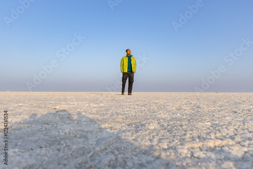 young man standing at white salt desert with bright blue sky at morning from low angle photo