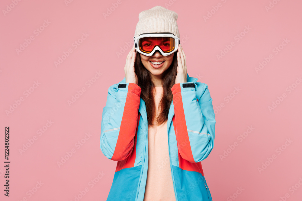 Snowboarder young smiling happy woman wear warm blue padded jacket touch ski goggles mask spend extreme weekend winter season in mountains look camera isolated on plain pink background. Hobby concept. Snowboarder young smiling happy woman wear warm blue padded jacket touch ski goggles mask spend extreme weekend winter season in mountains look camera isolated on plain pink background. Hobby concept.