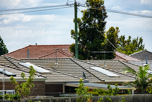 A row of houses with tiled roofs line a suburban street in Werribee, Melbourne. Concept housing, real estate, household, dwelling, residential neighborhood, and living in Australia. photo