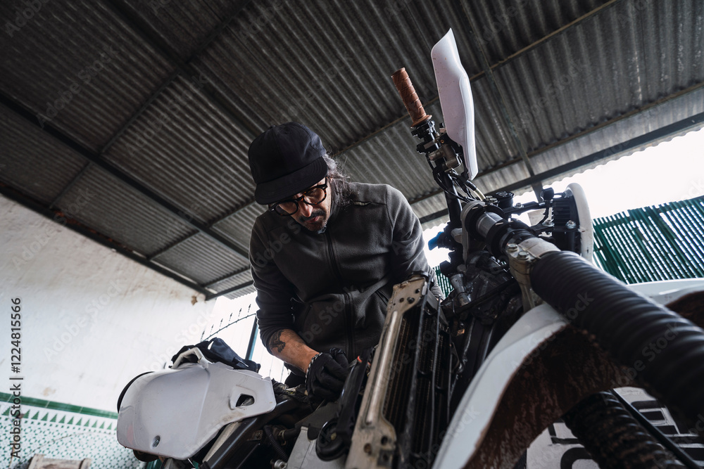 Hombre moreno con gafas poniendo a punto moto de cross para usar en el campo