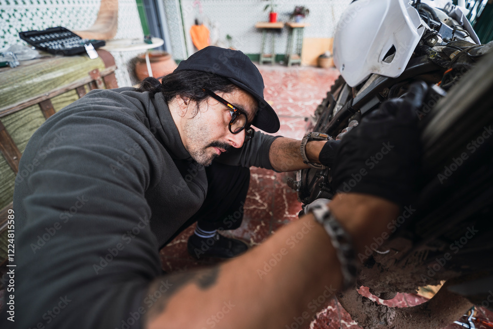 Hombre moreno con gafas poniendo a punto moto de cross para usar en el campo