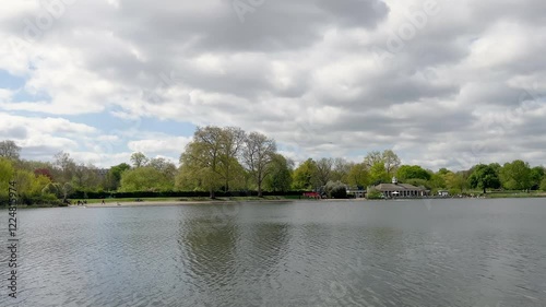 Lake, trees and cloudy sky view at public park in London.