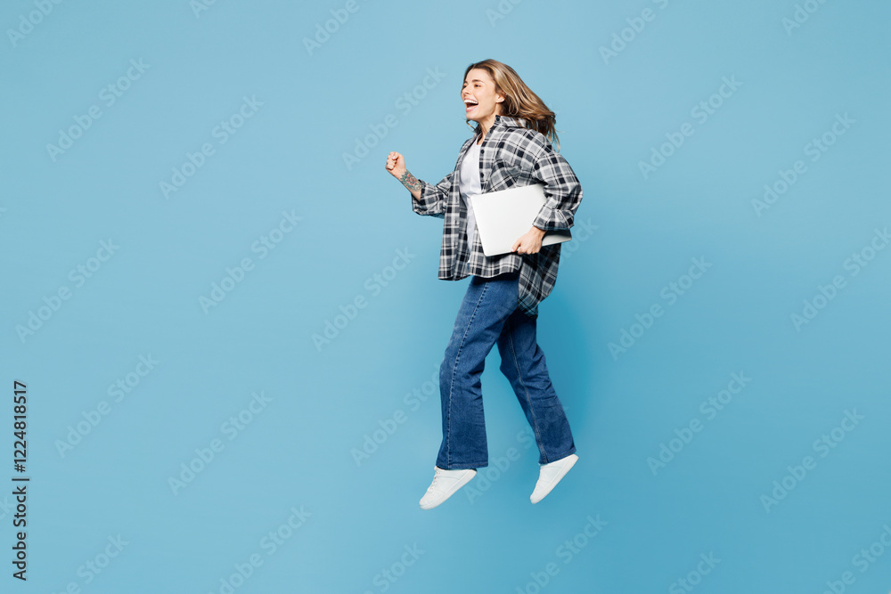 Full body young IT woman wears checkered grey shirt casual clothes jump high hold use work on laptop pc computer isolated on plain pastel light blue cyan background studio portrait. Lifestyle concept. Full body young IT woman wears checkered grey shirt casual clothes jump high hold use work on laptop pc computer isolated on plain pastel light blue cyan background studio portrait. Lifestyle concept.