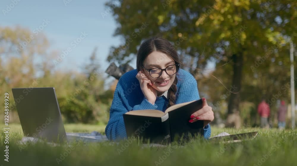 Girl with laptop reading outdoors in a quiet autumn park Girl with laptop reading outdoors in a quiet autumn park