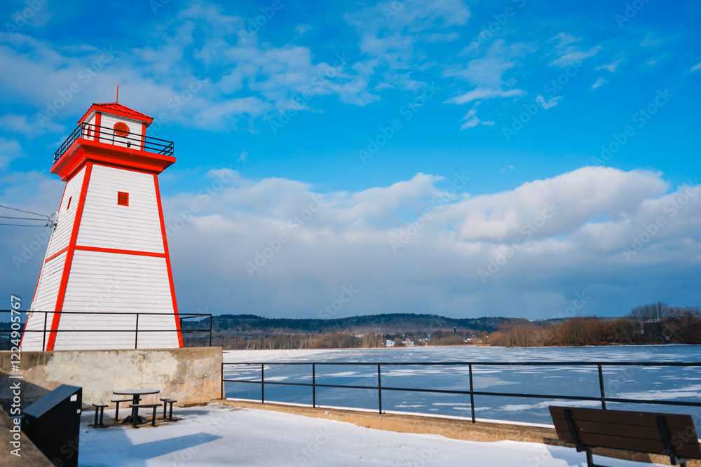 Naklejka premium Painted in red and white lighthouse by the river, winter, Grenville, Canada