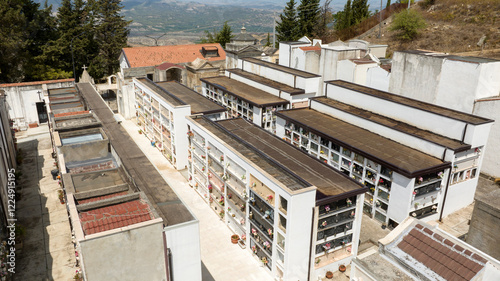 Fototapeta Naklejka Na Ścianę i Meble -  Aerial view of a small Christian Catholic cemetery. The streets between the chapels of the deceased are empty.