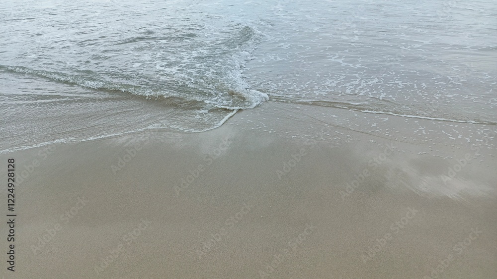 Close-up view of gentle waves lapping against the sandy shore, perfect for beach and relaxation themes Close-up view of gentle waves lapping against the sandy shore, perfect for beach and relaxation themes