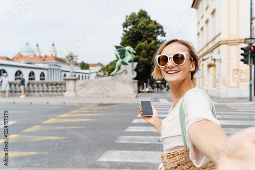 Young woman using smart phone sitting on Dragon bridge in Ljubljana. Travel Explore Slovenia, Europe