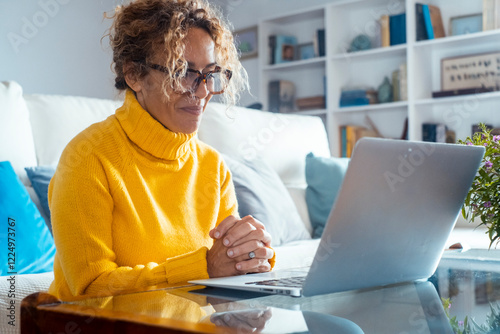 Canvas Print A confident mature woman seated at home, using her laptop to complete a project