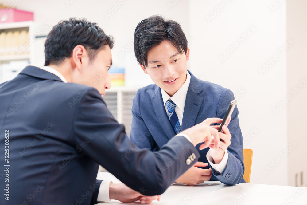 スマホを持って話をする二人のビジネスマン