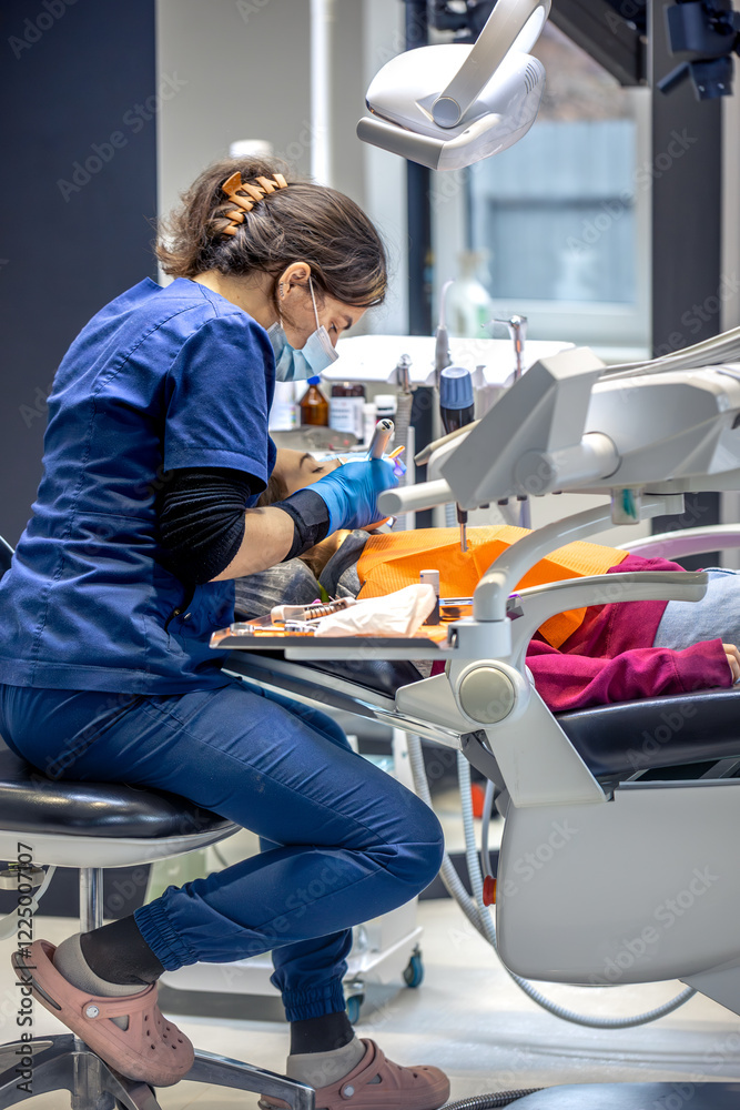 Fototapeta premium Young female dentist in dental office. Dentist at work. Dental treatment concept.