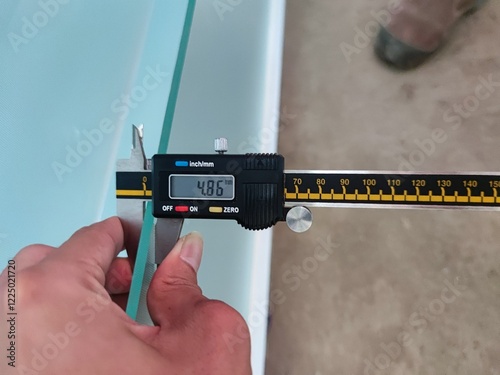 Digital caliper measuring the thickness of a glass panel to ensure accuracy in construction and safety applications