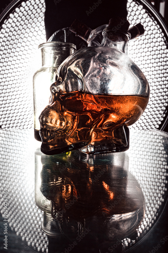 Glass skull whiskey bottle and mystical flasks on a black background with a beautiful background light