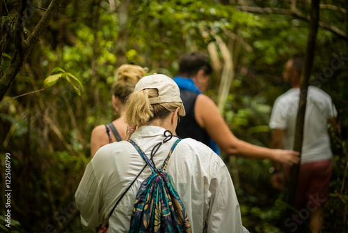 A small group navigates through dense foliage in a vibrant jungle, showcasing adventure and exploration in a thriving natural environment with diverse flora.