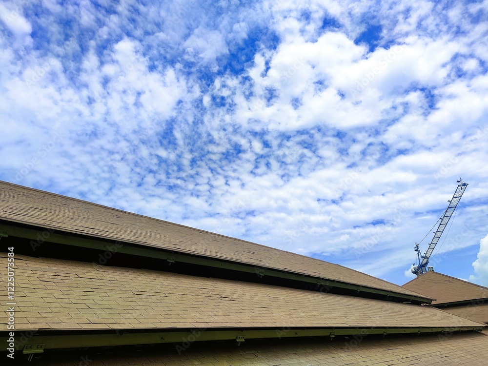 View of a worn asphalt shingle roof under a bright blue sky, showing visible damage and signs of aging on the roofing structure View of a worn asphalt shingle roof under a bright blue sky, showing visible damage and signs of aging on the roofing structure